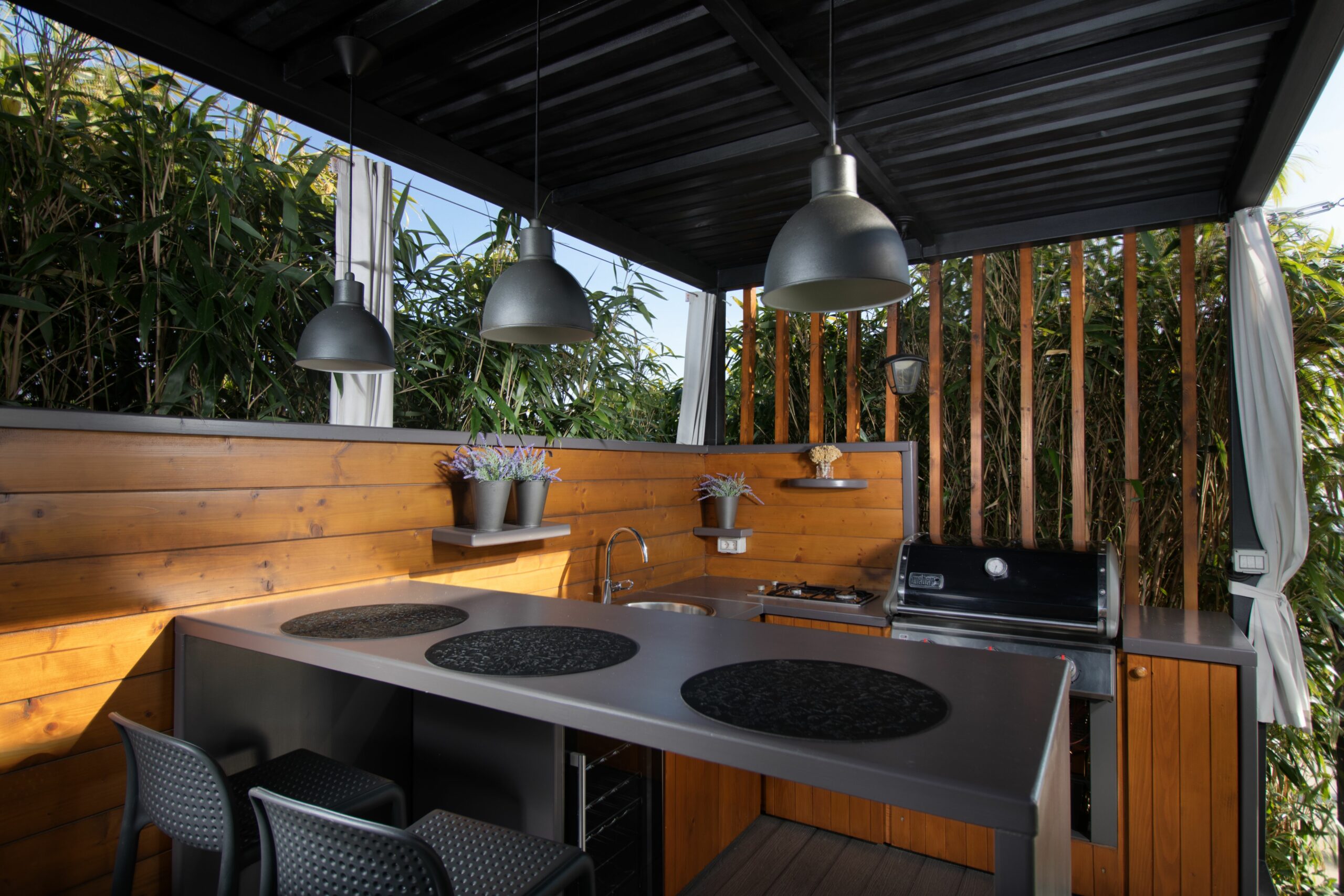 An open-air mini kitchen with wooden parts, trees and sky background